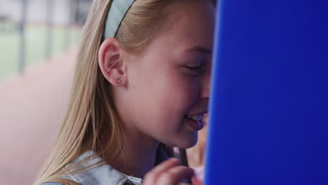 Video-of-two-diverse,-happy-schoolgirls-talking-by-lockers-in-school-corridor,-copy-space