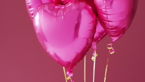 Video-of-four-shiny-pink-heart-shaped-balloons-floating-on-pink-background