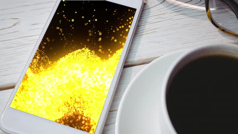 Animation-of-smartphone-with-light-trails-on-screen-and-cup-of-coffee-on-desk