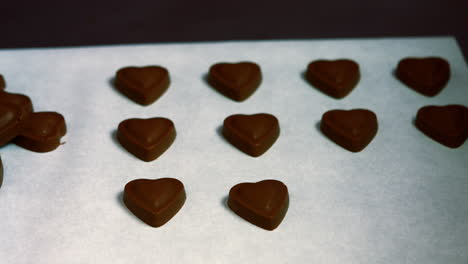 Worker-arranging-heart-shaped-dark-chocolate-on-tray