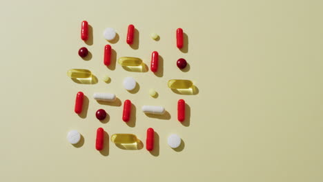 Video-of-a-variety-of-pills-and-capsules-arranged-on-yellow-background-with-copy-space