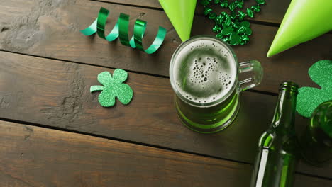 Video-of-st-patrick's-green-beer,-shamrock-and-bottle-on-wooden-background