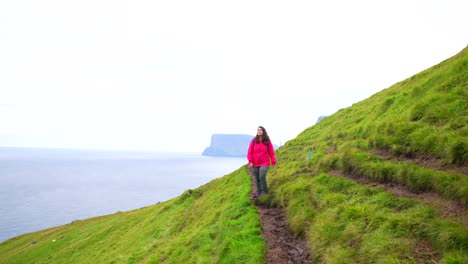 Woman-admires-Faroese-landscape-en-route-to-Kallur-Lighthouse,-Kalsoy