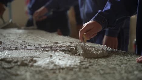 Group-Of-People-Working-As-Team-With-Trowel-Spreading-Cement-Over-Flat-Element