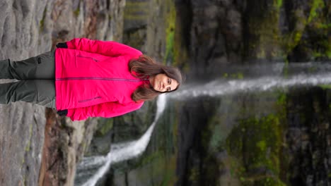Woman-admires-Mikladalur-waterfall-environment,-Faroese-landscape.-Vertical