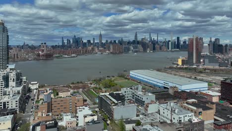 Aerial-backwards-shot-showing-Skyline-of-New-York-behind-East-River-during-sunny-and-cloudy-day---View-From-Brooklyn-District-with-noble-housing-area