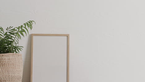 Holzrahmen-Mit-Kopierraum-Auf-Weißem-Hintergrund-Mit-Pflanze-Auf-Dem-Schreibtisch-Vor-Weißer-Wand