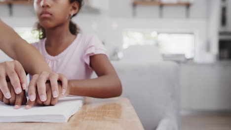 African-american-mother-and-daughter-reading-braille,-with-copy-space,-slow-motion