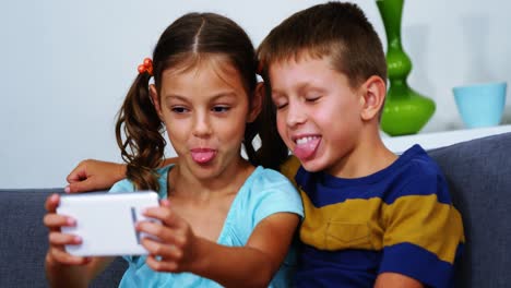 Siblings-taking-selfie-from-mobile-phone-in-living-room