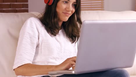 Smiling-woman-using-laptop-on-sofa-