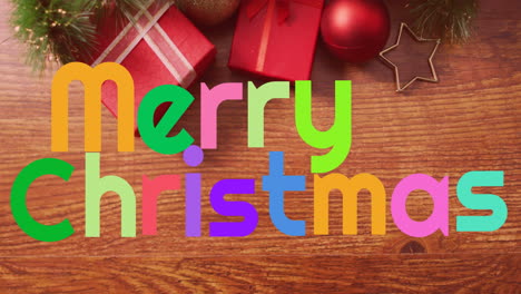 Animation-of-colorful-merry-christmas-text-banner-over-christmas-decorations-on-wooden-surface