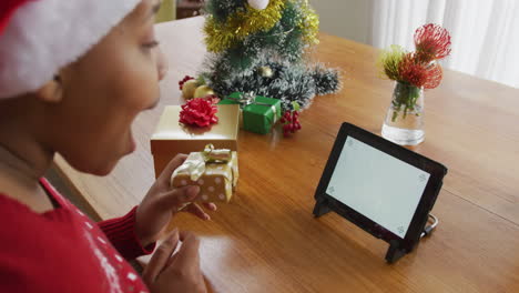 Feliz-Mujer-Afroamericana-De-Talla-Grande-Con-Sombrero-De-Papá-Noel,-Haciendo-Videollamadas-Usando-Una-Tableta-En-Navidad