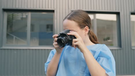 Young-woman-in-scrub-takes-pictures-using-digital-camera