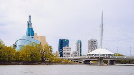 Bright-Overcast-Day-Over-the-Assiniboine-Red-River-Bank-in-Downtown-Winnipeg-Manitoba-Canada-with-the-Canadian-Museum-for-Human-Rights-and-Provencher-Bridge-in-the-Background