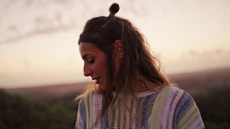 Face-of-shy-young-woman-touching-hair-while-looking-down-on-outdoor-at-sunset