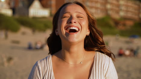 Slow-motion-shot-of-a-beautiful-woman-smiling-and-laughing-on-the-beach-at-sunset