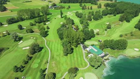 Captivating-drone-footage-of-an-Austrian-golf-resort,-nestled-beside-the-emerald-waters-of-Mondsee-lake