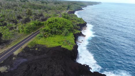 Klippen-Aus-Schwarzem-Vulkangestein-Und-Eine-Straße,-Die-Daran-Entlang-Durch-Den-Dschungel-Auf-Der-Insel-Hawaii-Führt