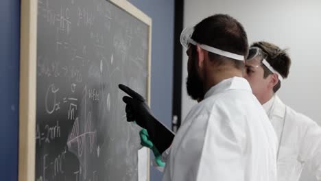 In-an-immersive-setting,-scientists-deliberate-over-complex-equations-on-a-blackboard,-highlighting-the-collaborative-spirit-and-rigorous-analysis-that-drive-scientific-breakthroughs
