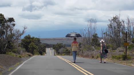 Two-women-walking-through-Volcano-National-park-Devastation-Trail-on-a-hot-Hawaiian-day-with-a-view-of-the-park-in-the-background