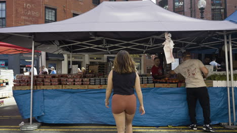 Slow-motion-shot-of-a-woman-looking-at-the-products-for-sale-at-a-street-market-in-Boston