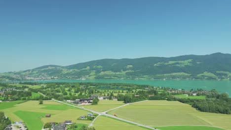 Lakefront-luxury:-The-drone-captures-serene-Mondsee-lake,-fringed-by-majestic-mountains,-with-a-glimpse-of-the-Austrian-golf-resort