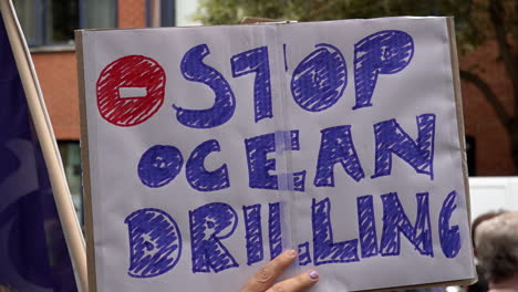 In-slow-motion-a-person-holds-up-a-placard-that-reads,-“Stop-ocean-drilling”-during-the-Restore-Nature-Now-protest
