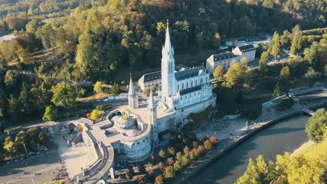 Aerial-tilting-establishing-shot-of-the-Lourdes-Cathedral-with-tourists-outside