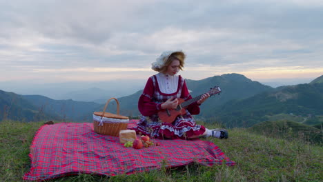 renaissance-medieval-traditional-clothing-female-model-playing-ukulele-while-having-meal-in-nature
