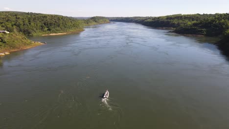 A-speedboat-travels-upstream-on-the-Paraná-River,-marking-the-boundary-between-Argentina-and-Paraguay,-symbolizing-the-international-connection-and-scenic-river-journey