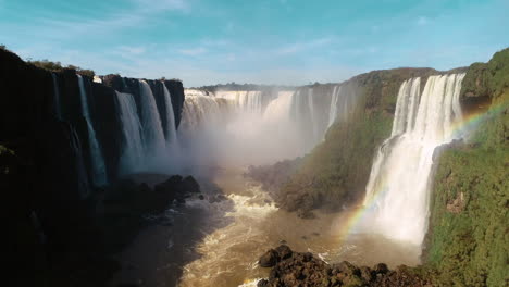 Bird's-eye-view-gracefully-approaches-the-magnificent-Iguazu-Falls-on-a-clear-blue-sky-day,-capturing-the-awe-inspiring-beauty-of-this-natural-wonder