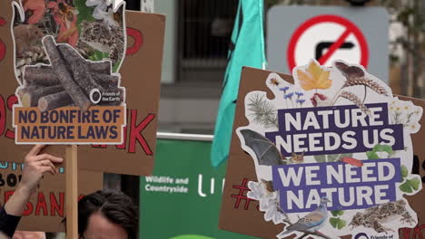 In-slow-motion-two-placards-held-up-read,-“No-bonfire-of-nature-laws”-and-“Nature-needs-us,-we-need-nature”-on-a-protest-outside-the-The-Department-for-Environment-Food-and-Rural-Affairs-