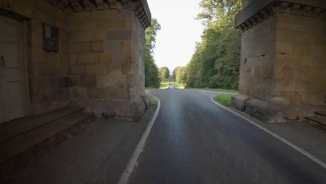 The-approach-road-to-Castle-Howard,-passing-through-large-archway-of-the-Pyramid-Gate
