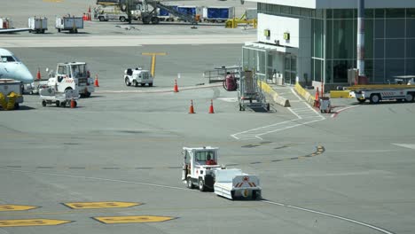 Man-Driving-A-Ground-Vehicle-Pulling-An-Empty-Baggage-Cart-in-The-Airport