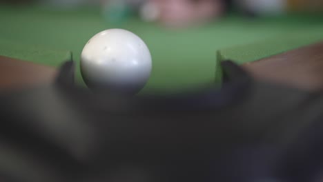 A-close-up-image-captures-the-detail-of-a-billiards-table-with-a-white-cue-ball-striking-and-knocking-another-ball
