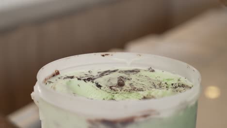 Hands-scooping-green-ice-cream-with-chocolate-from-a-container