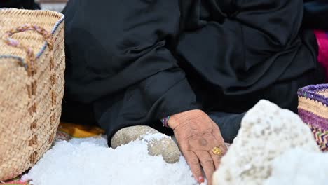 Una-Mujer-árabe-Pulverizando-La-Sal-Marina-A-Mano,-Tradicionalmente-Usando-Una-Roca.