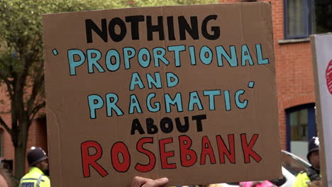 In-slow-motion-a-improvised-cardboard-placard-reads,-“Nothing-proportional-and-pragmatic-about-Rosebank”