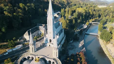 Aerial-establishing-shot-of-the-Lourdes-Cathedral-with-tourists-queueing-outside