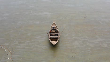 Aerial-shot-of-a-lonely-wooden-fishing-boat-on-the-shore-of-a-beach-in-Bangladesh