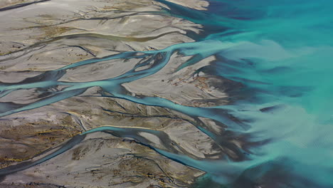 Stunning-aerial-drone-view-of-the-turquoise-water-of-Lake-Pukaki-meeting-the-Tasman-River-delta-on-New-Zealand's-South-Island