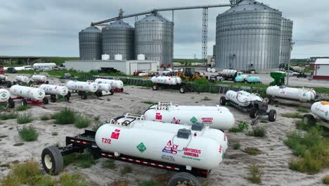 Industrial-site-with-large-silos,-anhydrous-ammonia-tanks,-and-equipment,-set-against-a-cloudy-sky