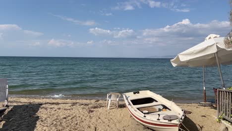 Perea-Strand-Mit-Sonnenschirm-Und-Verlassenem-Boot-In-Der-Nähe-Von-Thessaloniki-In-4k-Mit-Dem-Ägäischen-Meer-Im-Hintergrund