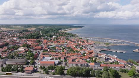 Aerial-sideways-over-small-city-Simrishamn-in-Sweden-on-a-sunny-cloudy-day