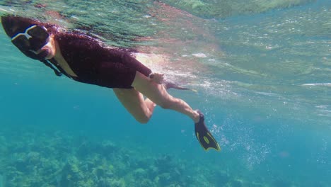 Beautiful-woman-snorkels-over-shallow-coral-reef-in-Roatan,-Honduras
