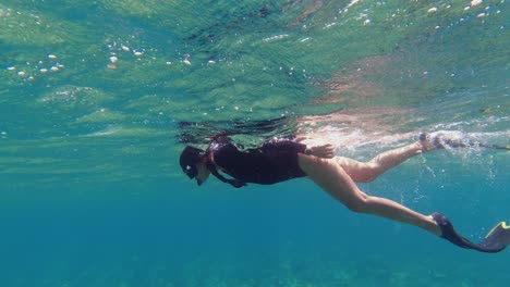Pretty-woman-with-braids-swims-with-mask-and-snorkel-in-warm-water