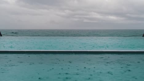 Still-clip-of-rain-drops-falling-on-the-water-surface-in-a-beach-side-pool