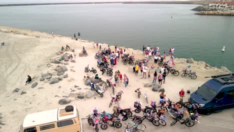 Group-of-cyclists-and-bike-packers-on-the-seashore-near-the-sea,-aerial-orbital