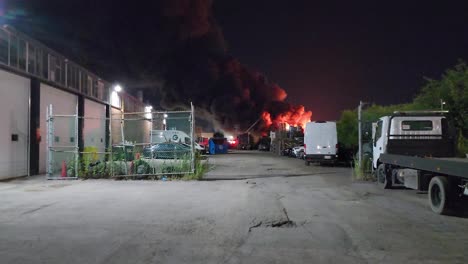 Large-plume-of-smoke-from-urban-fire-rises-high-into-night-sky,-industrial-scene