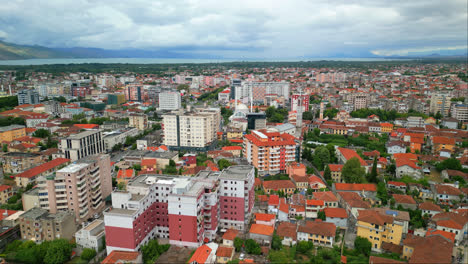Aerial-drone-backward-moving-shot-over-residential-buildings-in-Shkodra,-also-known-as-Shkoder-or-Scutari-along-north-west-of-Albania-on-a-cloudy-day